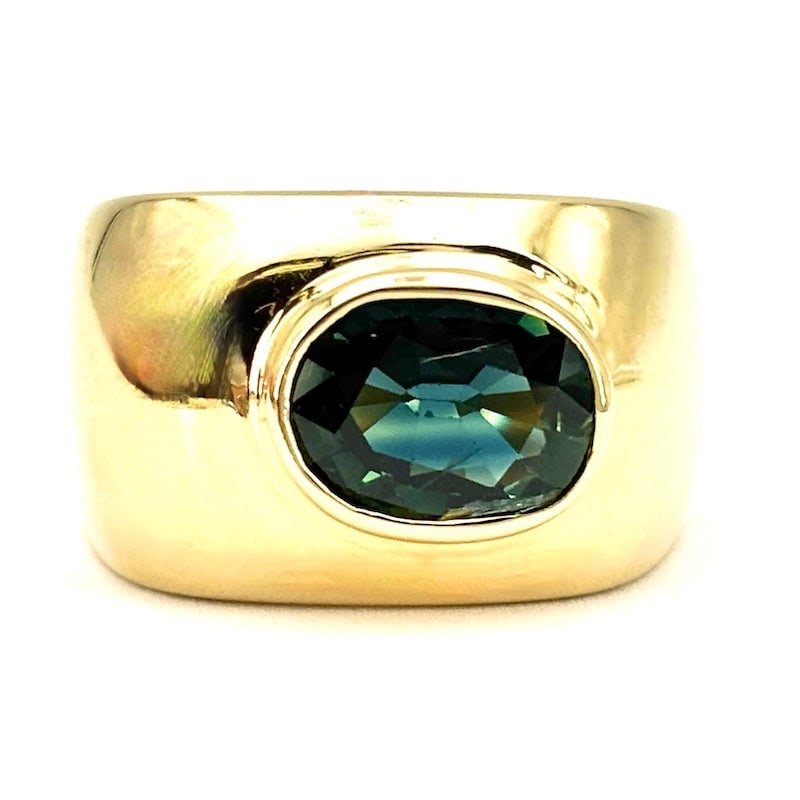 Men's band bridge ring, petrol sapphire, yellow gold; 7.02 gr: A special, unique, and characterful men's jewel! Unisex band ring, bridge style, in 18kt yellow gold, with an oval-cut sapphire in an unusual petrol blue hue, in a very solid, rounded, square, mirrore