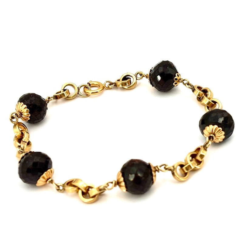 Vintage maxi garnet and gold bracelet; 28.2 g: Charismatic and sophisticated vintage bracelet in a retro style, with large irregular faceted garnet spheres intertwined in 18kt yellow gold, with iconic flower caps and gold chain inserts. An unusual