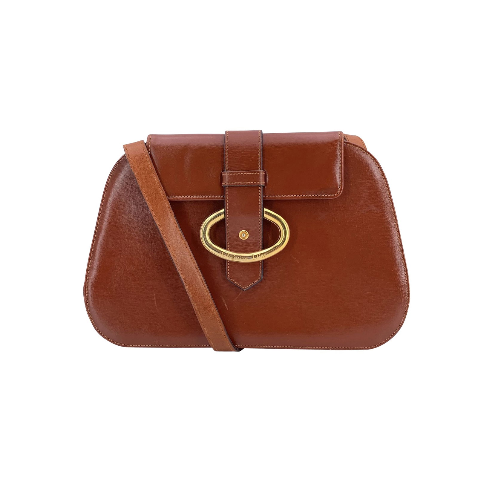 Dior Vintage Leather Shoulder Bag: Crafted in tan brown leather with a solid finish, the bag features a graceful oval silhouette that feels both feminine and architectural. On the front, a slim gold metal clasp frames the edge of the f
