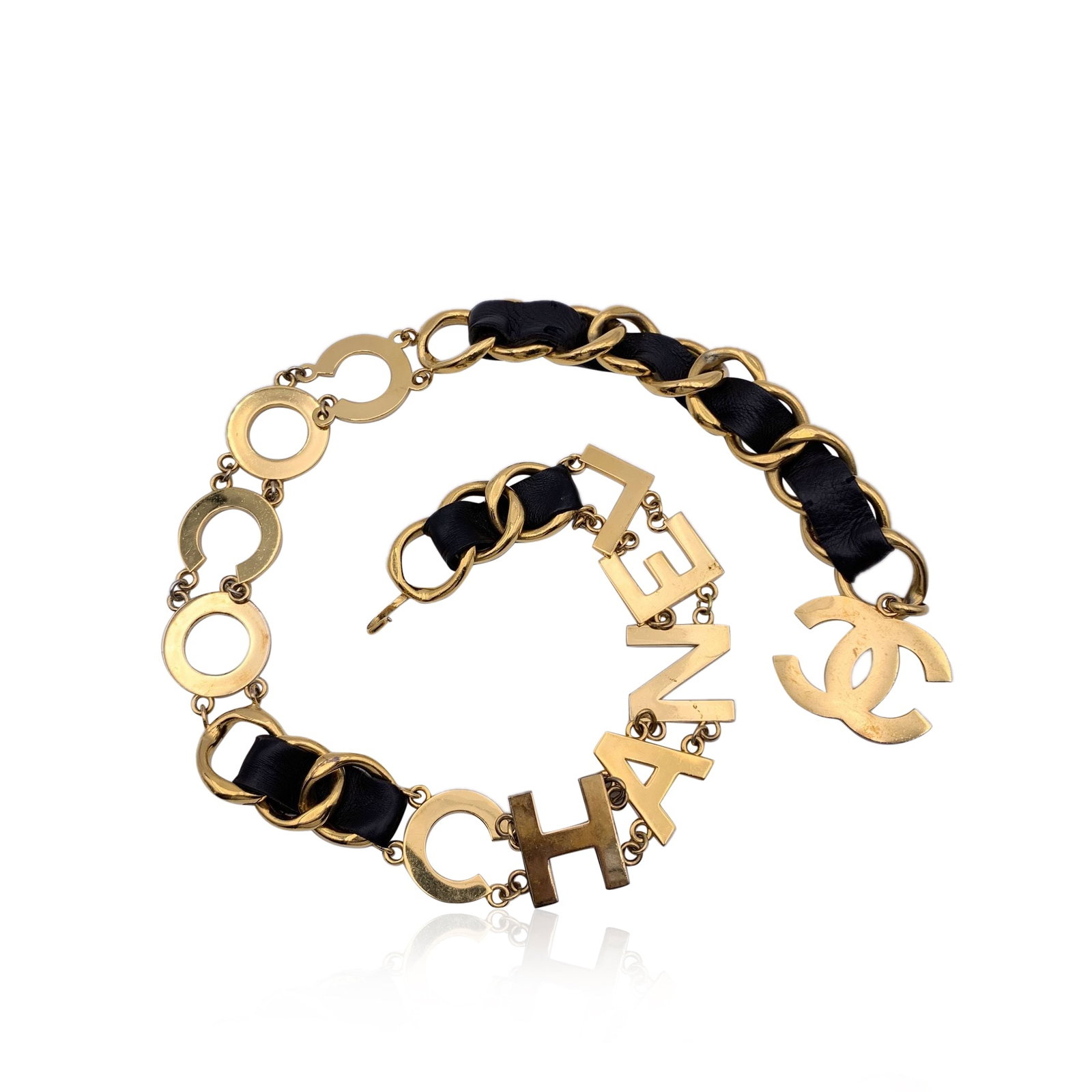 CHANEL VINTAGE METAL BELT: Rare statement vintage wide chain belt by CHANEL. Period/Era: 1993. It is crafted in gold metal with black interwoven leather. It features a spell out C O C O C H A N E L letters. CC logo pendant at t