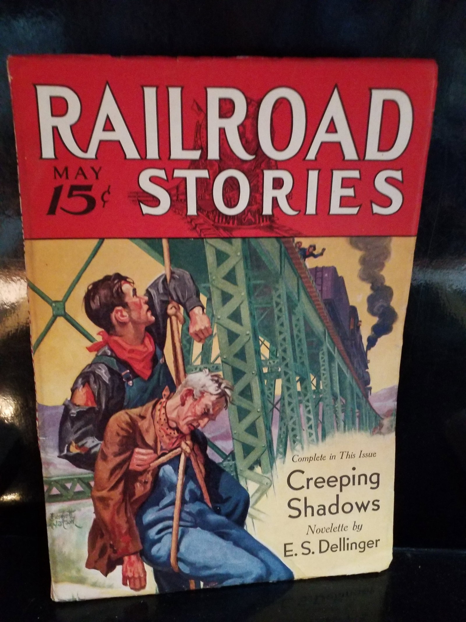 May 1933 Railroad Stories magazine Pulp comic book Featuring Creeping Shadows by Dellinger F+: Featured Story: "Creeping Shadows", a railroad-themed novelette by E. S. Dellinger. Cover Art: Features two railroad workers on a steel bridge structure with a steam locomotive passing by in the backg
