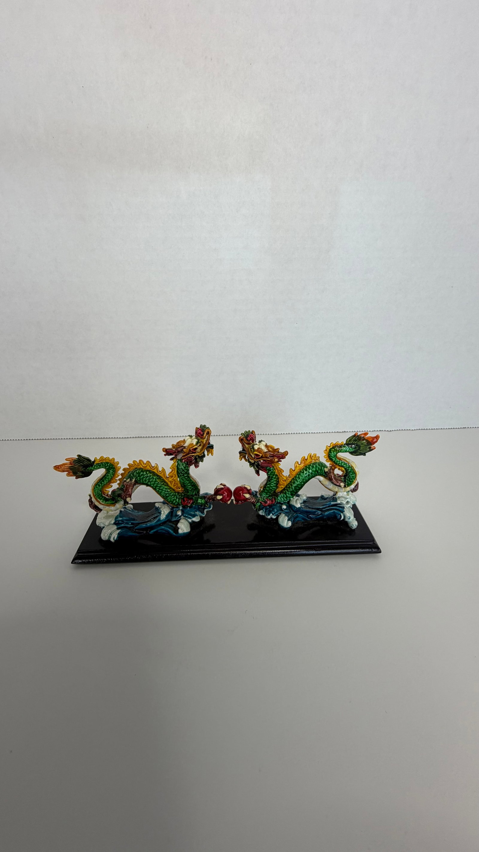 Twin Chinese Dragons with Flaming Pearl on Stylized Waves: A vivid and symbolic Chinese dragon figurine, featuring two intricately detailed dragons in mirrored stances, facing each other atop stylized crashing waves, with a shared red orb or flaming pearl sus