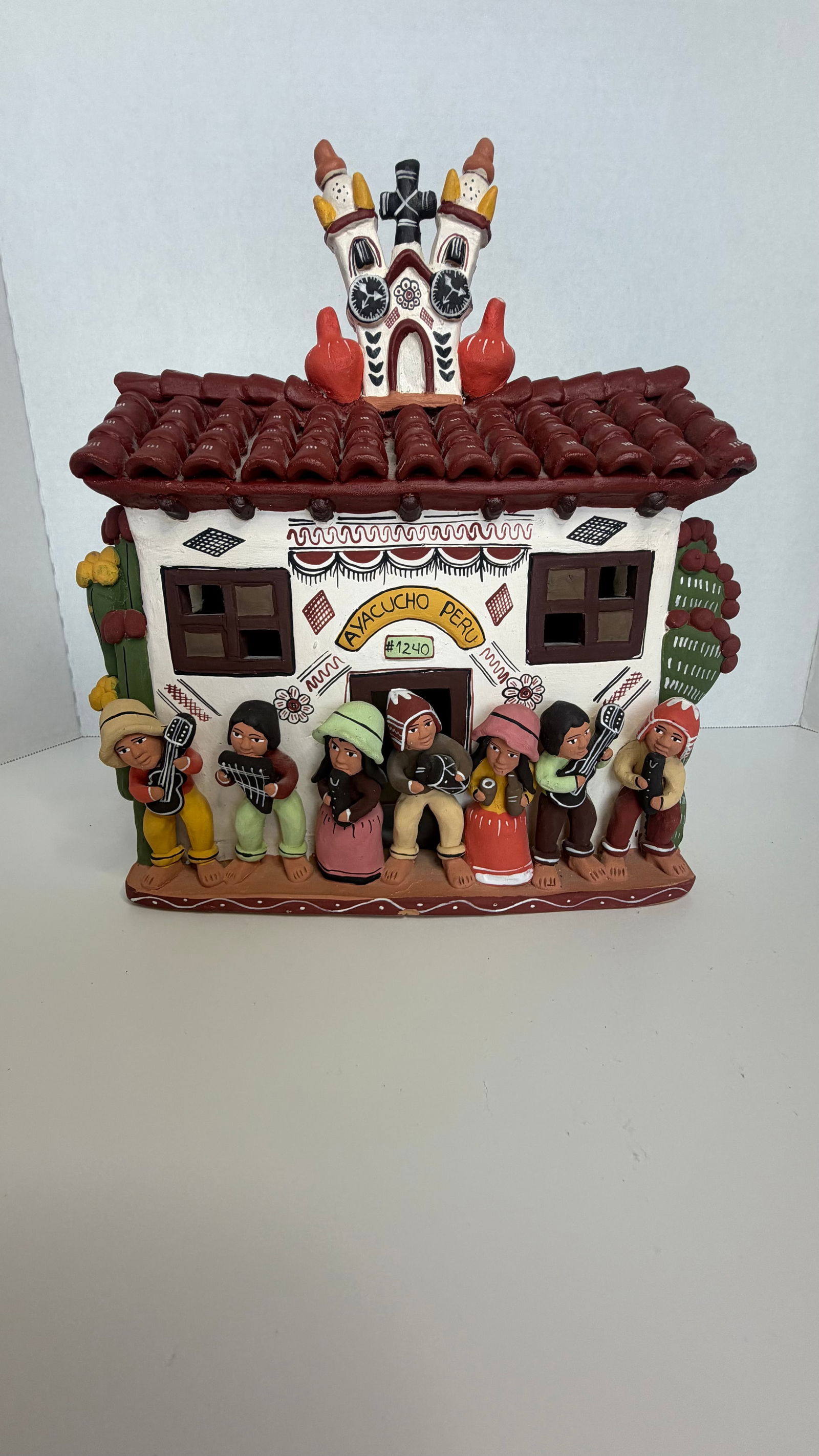 Handcrafted Peruvian Ceramic Retablo House: “Ayacuchan Pub”: A delightfully vibrant Peruvian ceramic retablo-style house, richly detailed and brimming with folkloric charm. Titled Ayacuchan Pub, this piece is a celebration of Andean village life, capturing the