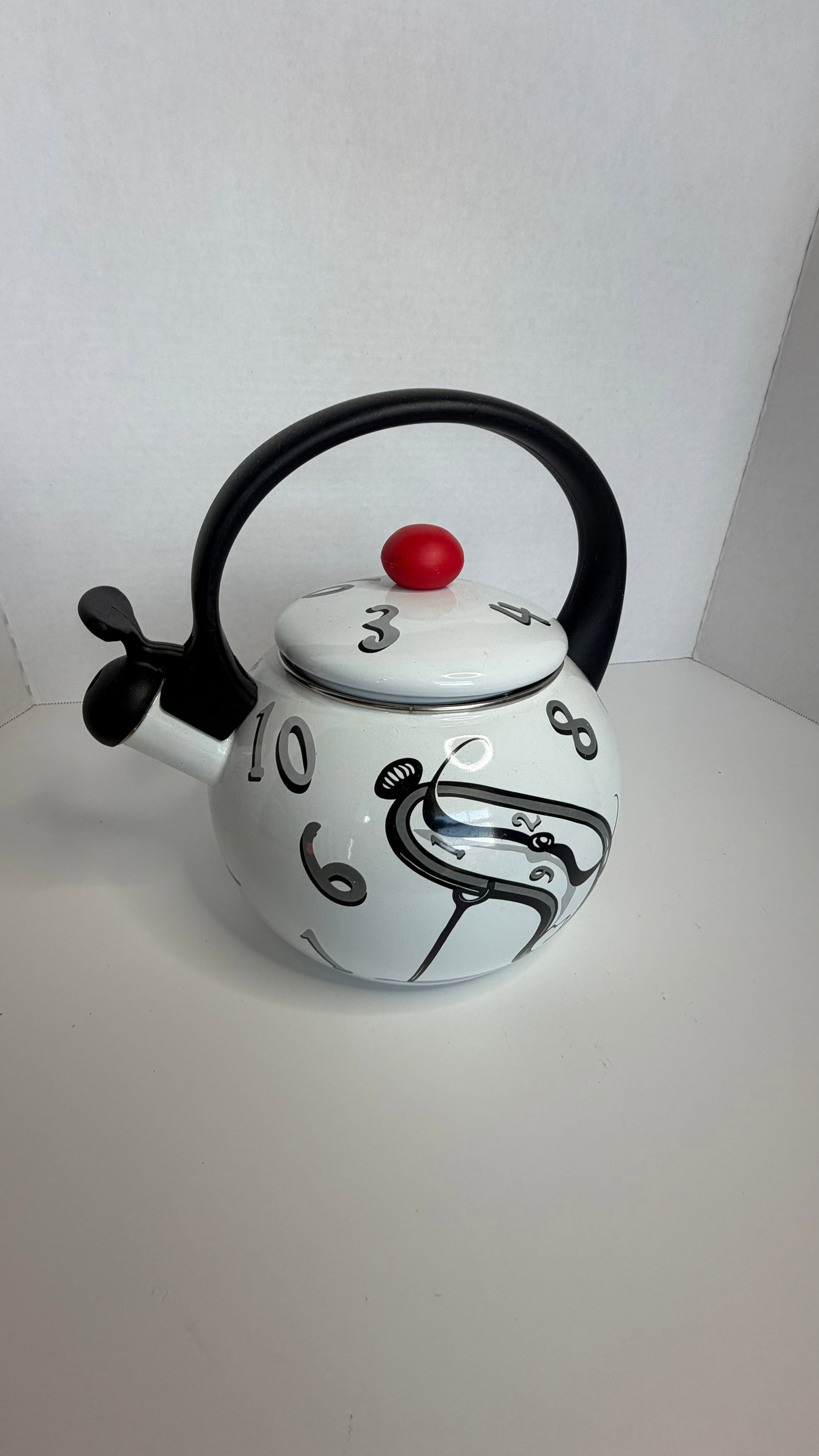 Postmodern Whistling Kettle with Surrealist Clock Motif - Salvador Dali: A visually striking enamel-on-steel whistling kettle, notable for its whimsical postmodern design featuring distorted clock numerals and bold, graphic lines in the style of surrealist timepieces. The