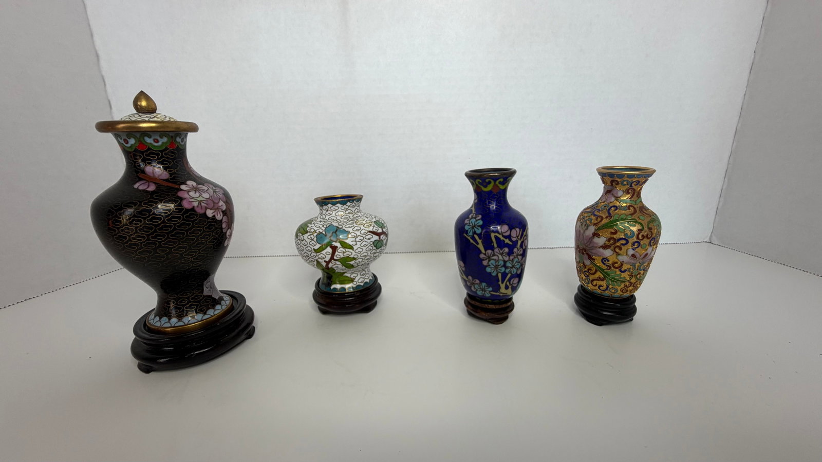 Set of Four Cloison Enamel Vases with Lidded Ginger Jar; Chinese Style: A refined quartet of cloison enamel vases, showcasing the timeless artistry of a technique that dates back to antiquity and reached its pinnacle in imperial Chinese decorative arts. Each vase is adorn