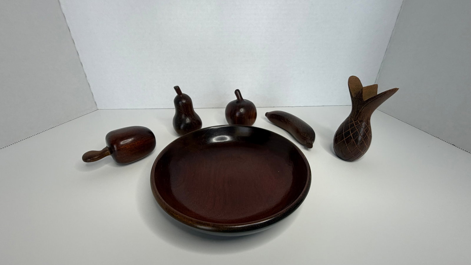 Handcrafted Wooden Fruit Bowl with Sculpted Fruit – 6-Piece Set: A beautifully handcrafted decorative wooden fruit bowl set, featuring five individually carved fruits and a smooth matching display bowl. Sculpted from dark-stained Brazilian hardwood, each fruit̵