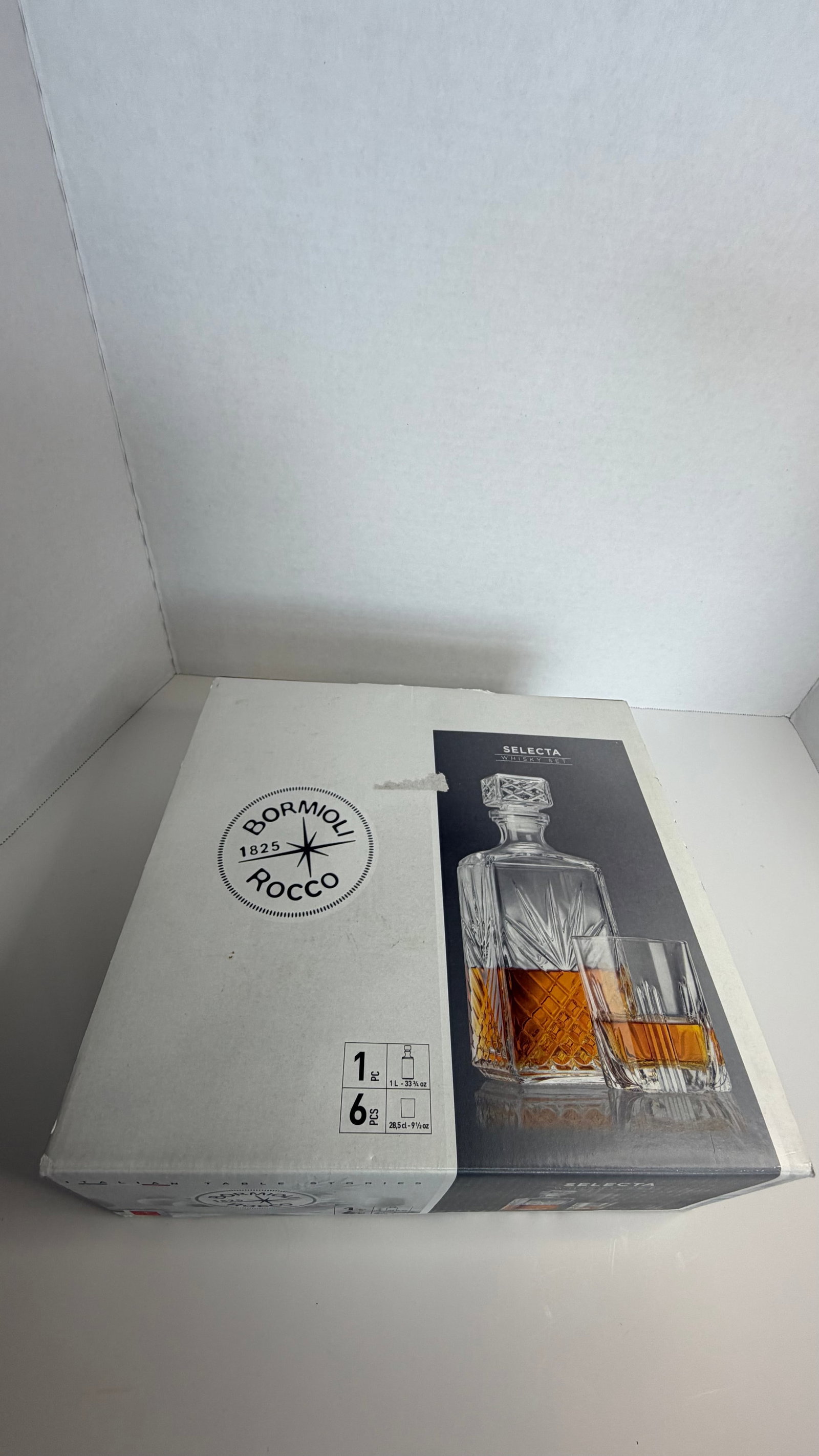 Crystal-Cut Whiskey Decanter Set with Six Matching Tumblers: A distinguished whiskey decanter set, exquisitely crafted in crystal-cut glass, featuring a square-profile decanter with a faceted stopper and six matching tumblers. Each piece showcases a classic sta