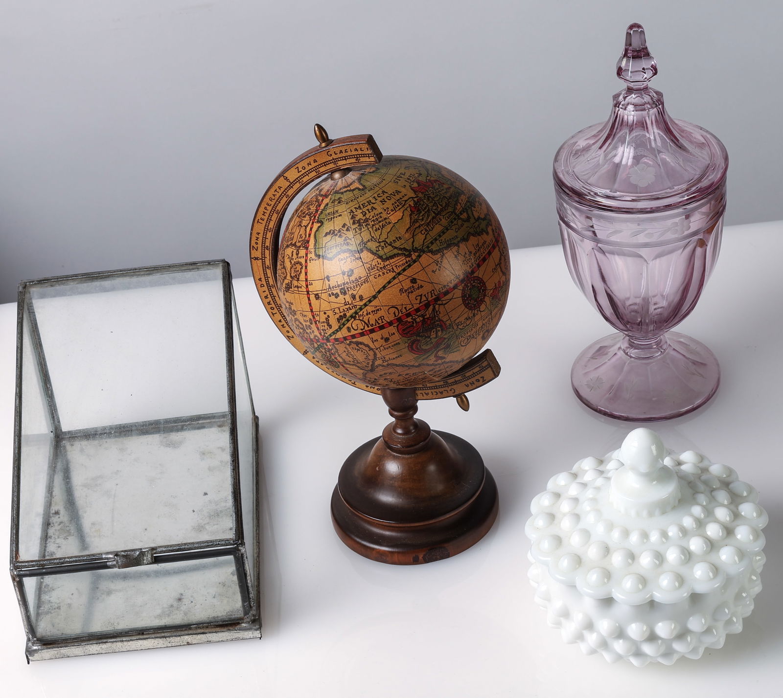 (4 pc) Vintage Estate Decor: (4 pc) Vintage Estate Decor: Metal-framed glass vitrine, vintage globe on wooden stand, amethyst glass lidded urn with etched decoration, and white hobnail milk glass covered dish. Size: 11'' x 6'' x