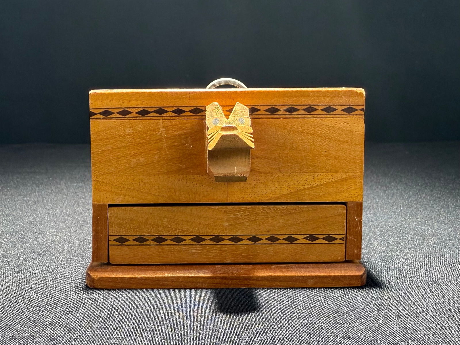 Wooden Cigarette Box with Dog Motif and Floral Inlay, circa 1940s: A charming wooden cigarette box featuring a carved dog head design serving as both decorative element and cigarette rest. The box is embellished with inlaid diamond patterns around the perimeter and a