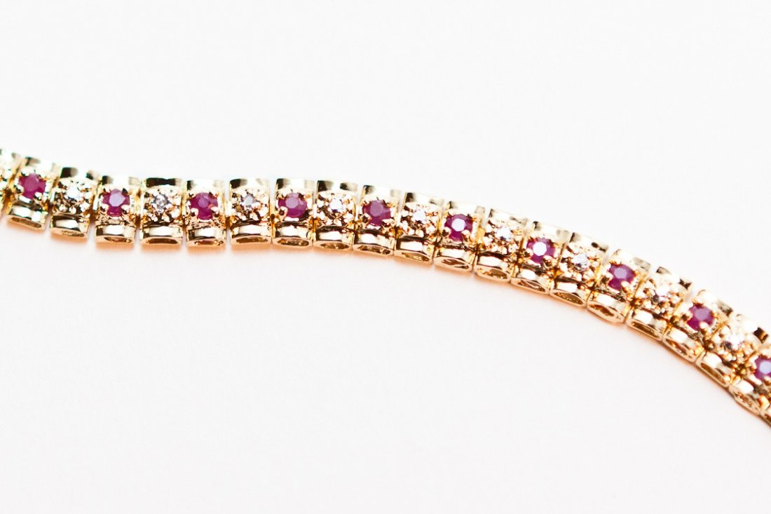 1.83 CTW Diamond and Ruby Tennis Bracelet: Master jewelers designed your bracelet with 29 single cut diamonds. 29 pieces of cabochon rubies. 11.4 grams of sterling silver layered with 18K gold. Length is 7 1/2 inches.