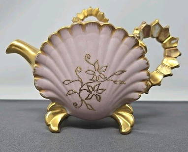 Jean Pouyat Limoges Pink Gold Shell Shape Teapot: Jean Pouyat Limoges pink and gold teapot. Shell shaped pattern with gold flowers. Unique handle and feet. Circa 1890 to 1900. Approximate measurements: 5 inches tall, 7 inches handle to spout, and 3 i