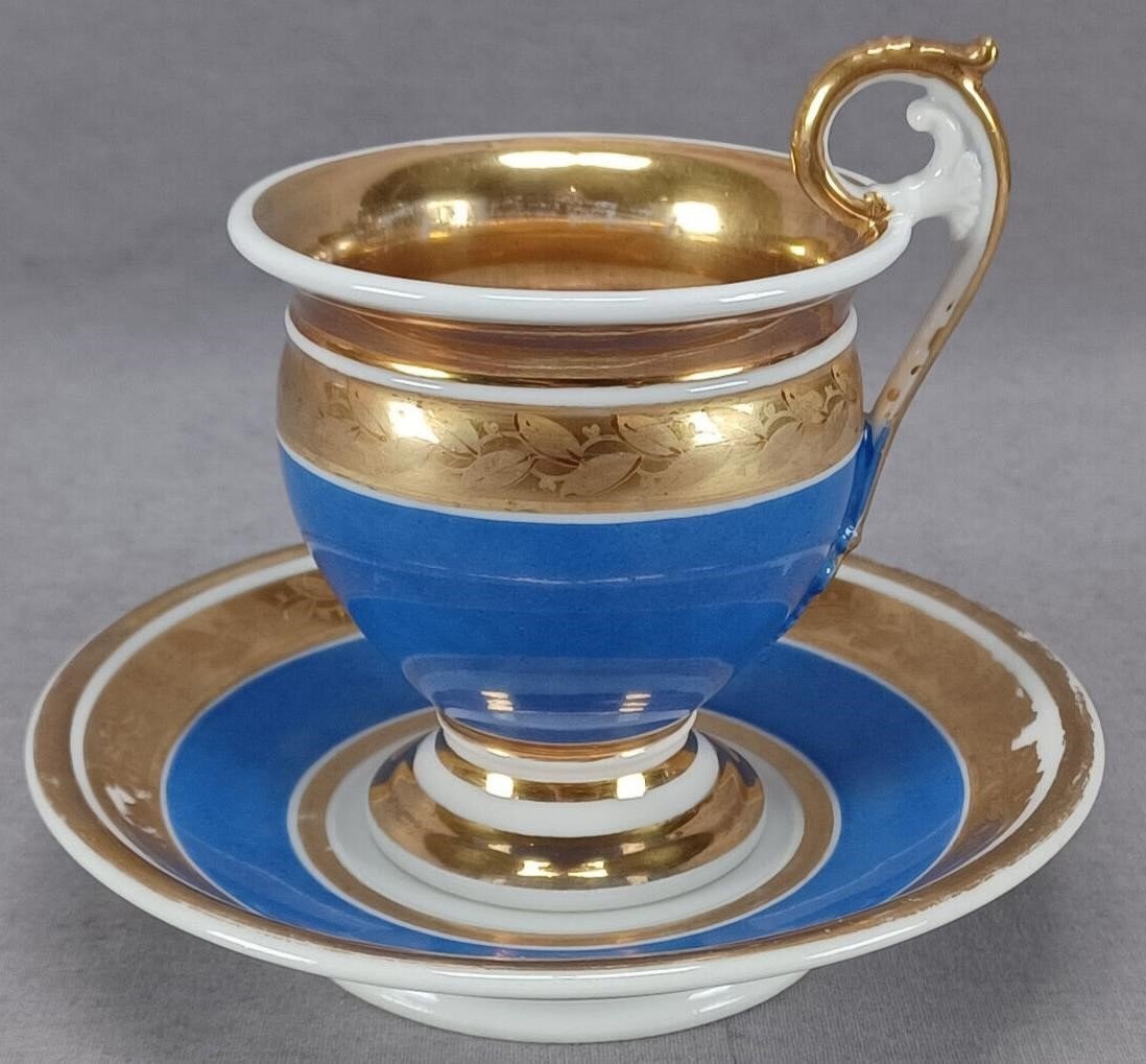 Old Paris Porcelain Gold Leaves Blue Cup & Saucer: Antique Old Paris / Vieux Paris empire form cup and saucer. Decorated with gold leaves over a gold band above blue. Gold gilding along the rim. Unmarked. Circa 1815.Has some wear to the gilding and an