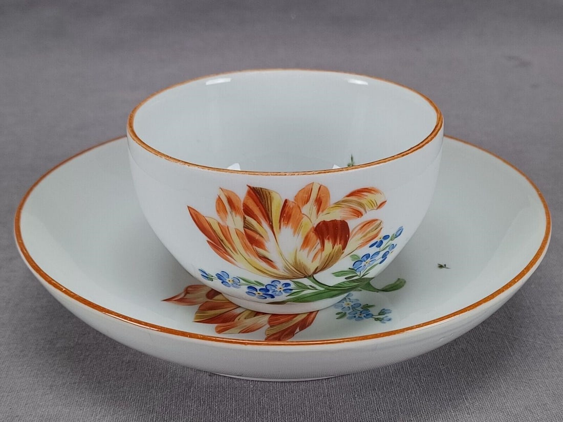 Meissen Marcolini Orange Floral Tea Cup & Saucer: Nice porcelain tea cup and saucer. Decorated with hand painted orange flower and blue forget me nots. Ocher trim along the edge and puce flower painted on the handle. Marked on the bottom with the blu