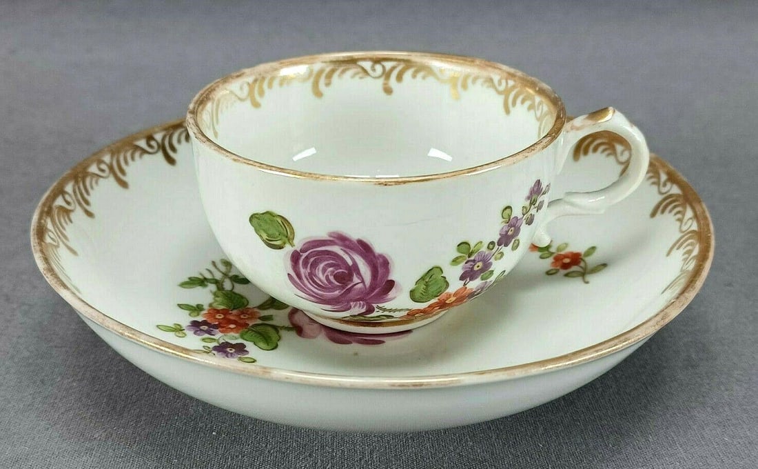 18th Century Royal Vienna Tea Cup & Saucer A: Nice antique 18th century "Royal Vienna" porcelain tea cup and saucer. Decorated with hand painted purple rose, and other purple and orange flowers. With gold gilt scrollwork along the edge. Marked on
