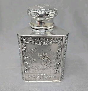 German Silver Repoussé Tea Caddy Romantic Scene: Unmarked German Silver tea caddy. It has three sides, with the same scene on each with a girl and birds. Polishes like silver but there are no marks. Measures approximately 3 1/4 inches tall and 1 3/4