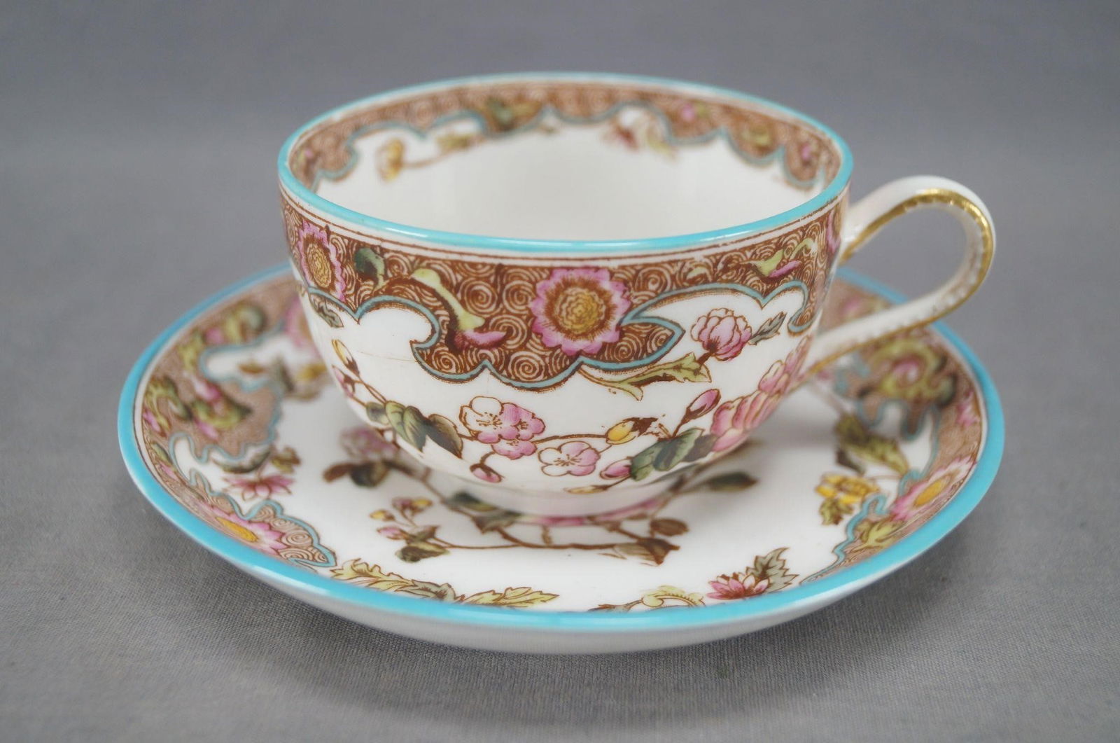 George Jones Kio Pattern Tea Cup & Saucer: Nice antique bone china tea cup and saucer. Decorated in the Kio pattern with hand colored pink and yellow flowers and turquoise enamel. The saucer is marked on the reverse with a crown over Anglo GJ