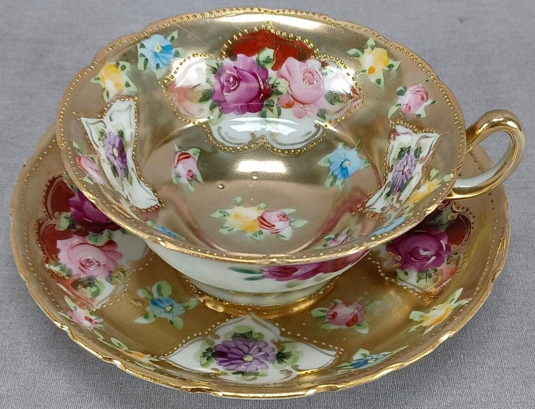 Nippon Hand Painted Floral Gold Tea Cup & Saucer D: Nice antique Japanese porcelain tea cup and saucer. The cup is decorated on the outside with dark pink roses. Decorated on the inside of the cup and on the saucer with hand painted pink and yellow ros