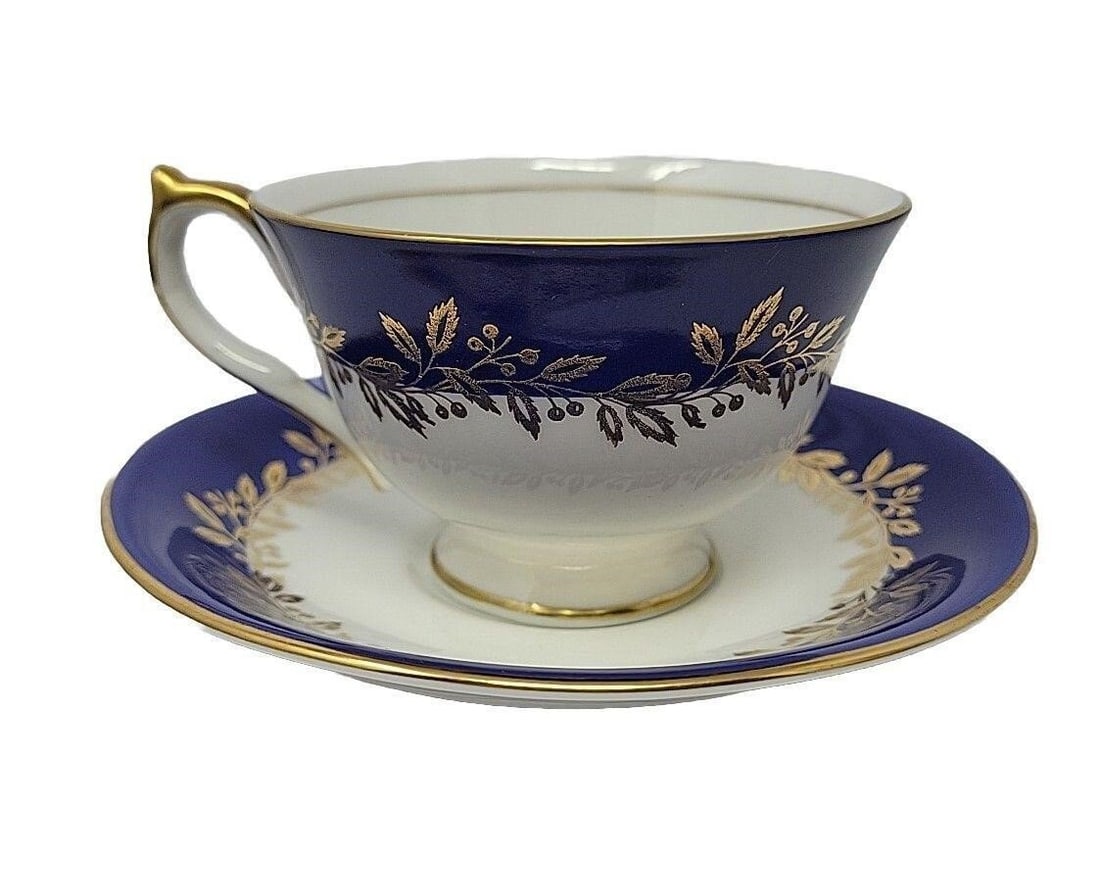 Aynsley Cobalt Blue and Gold Tea Cup and Saucer: Aynsley footed cup & saucer set with cobalt blue, gold leaf, and berry garland with fruit on bottom of cup. Pattern # 2966. Very good condition with no chips or cracks. There are a few light scratches