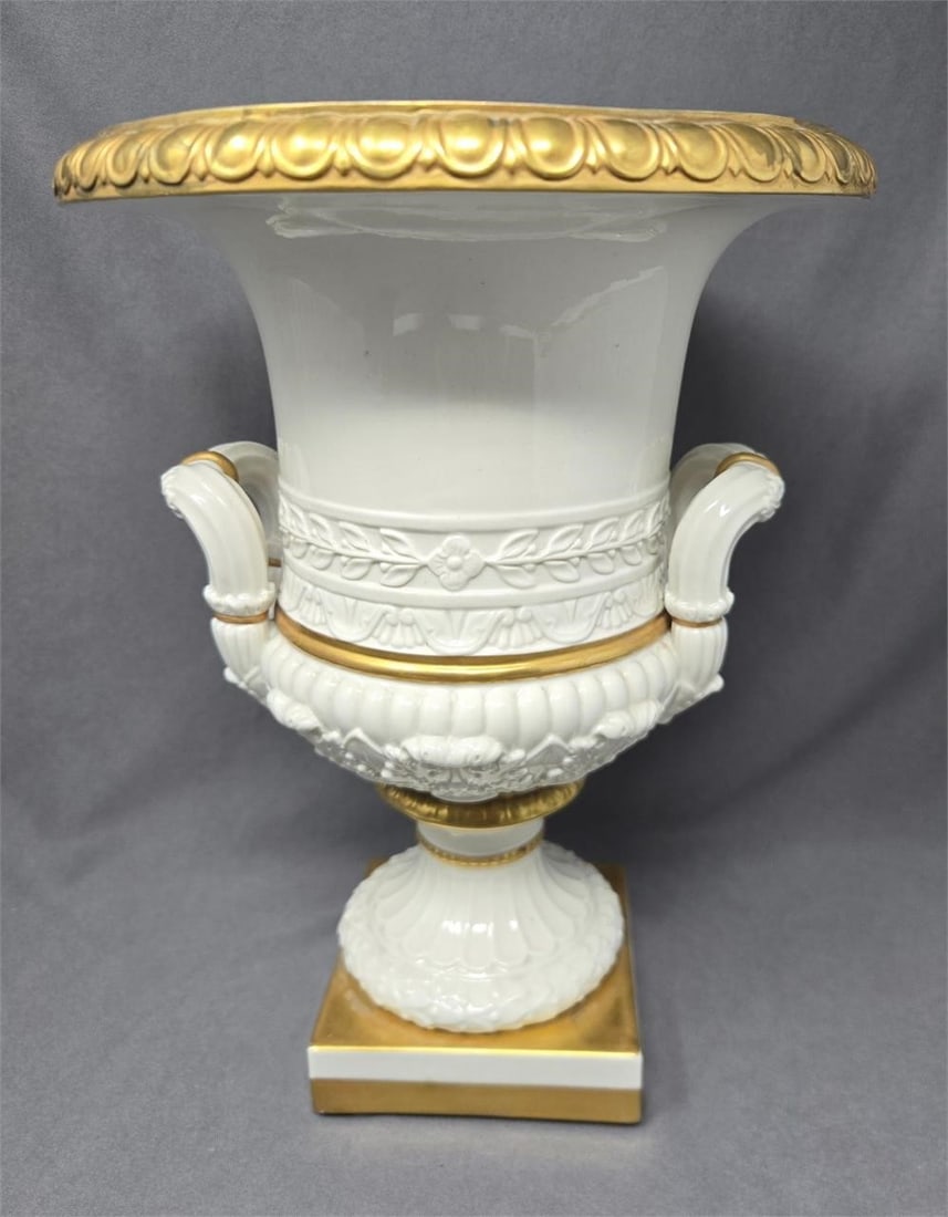Mottahedeh Porcelain Urn 10 1/2" 20th C: Mottahedeh white with gold accents urn. Measures approximately 10 1/2 inches tall and 8 inches wide at top. It sits on a square base. There is a hairline crack on the base, no other damage. There is s