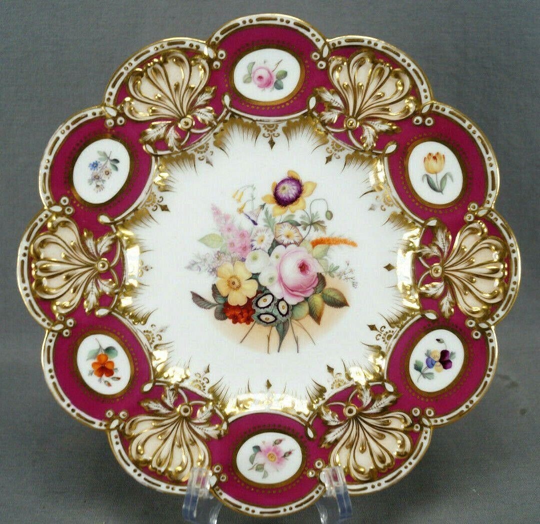 Coalport Hand Painted Floral Cranberry Plate: Nice mid 19th century plate with relief molded Rococo floral and scrollwork border in cranberry, peach/apricot and gold gilding with small hand painted flowers in gold ovals and gold dots. Has a hand