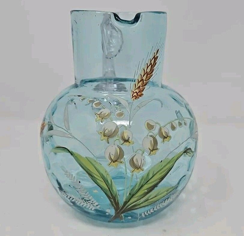 Harrach Lily Of The Valley Art Glass Jug Pitcher: Bohemian Harrach pitcher in blue glass. Hand enameled lily of the valley on coin dot background with an applied clear handle. Measures approximately 4 7/8 inches tall and 3 3/4 inches wide. There are