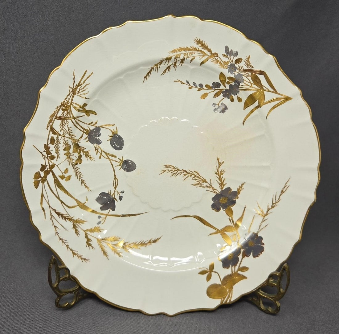 Minton Gold and Platinum Aesthetic Plate19th C.: Minton hand painted gold and platinum wildflowers and grasses on cream plate with a gold gilt border. Measures approximately 9 inches in diameter. There is crazing and a stain on the front and back. T