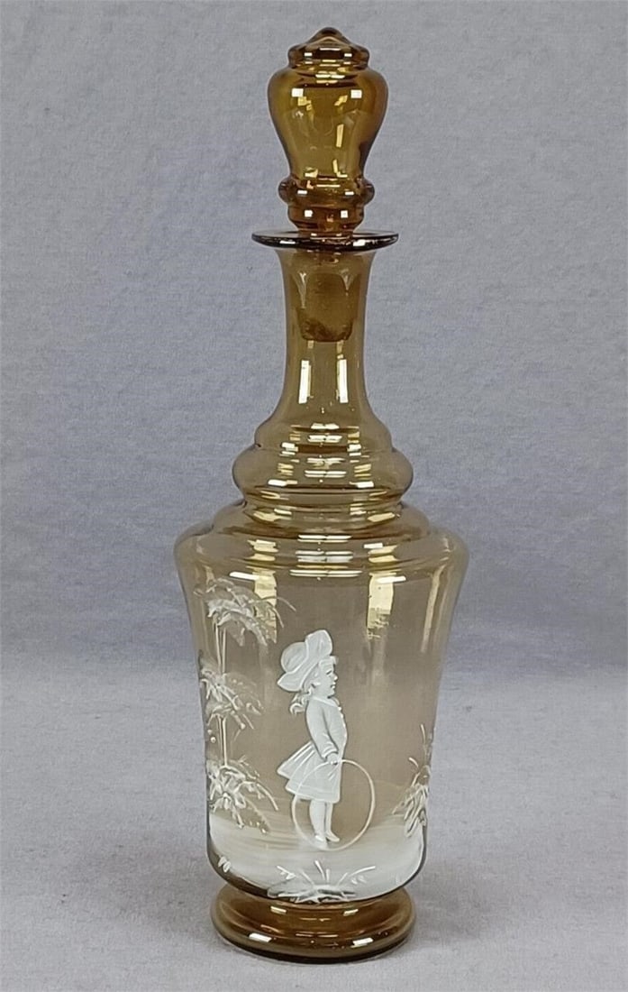 Mary Gregory Enameled Amber Glass Dresser Bottle: Nice antique Bohemian blown amber glass dresser bottle. Decorated with a hand painted in the Mary Gregory style with a little girl with a hoop in white enamel. Also known as snow glass. Gold gilding a