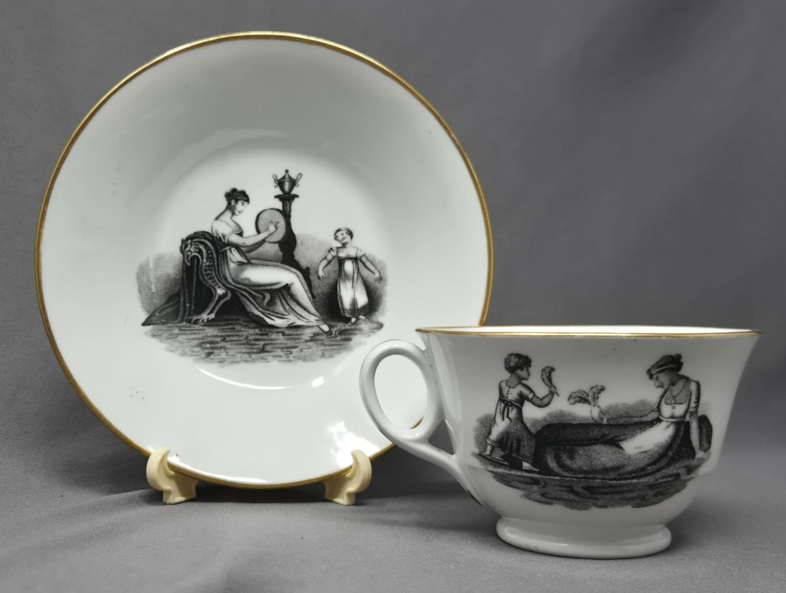 New Hall Mother & Child Transfer Cup and Saucer: New Hall black transfer cup and saucer set. Depicts three scenes of a mother and child. Circa 1800 to 1815. Plate 252 in the Compendium of British Cups by Michael Berthoud. No chips or cracks, some lo