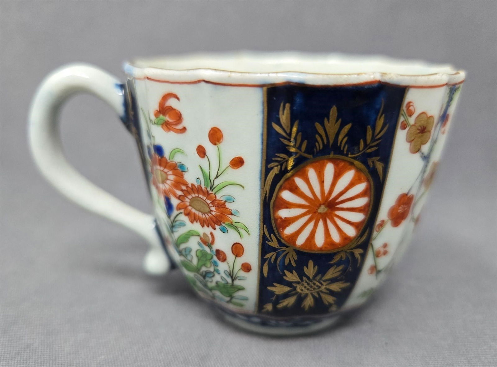 Worcester Kakiemon Imari Style Cup c. 1770s: First Period Worcester Kakiemon small cup. It has the seal mark and is circa 1770s. No chips or cracks, there is a loss to gold gilt on the rim. Hand painted floral panels on a ribbed pattern sides.