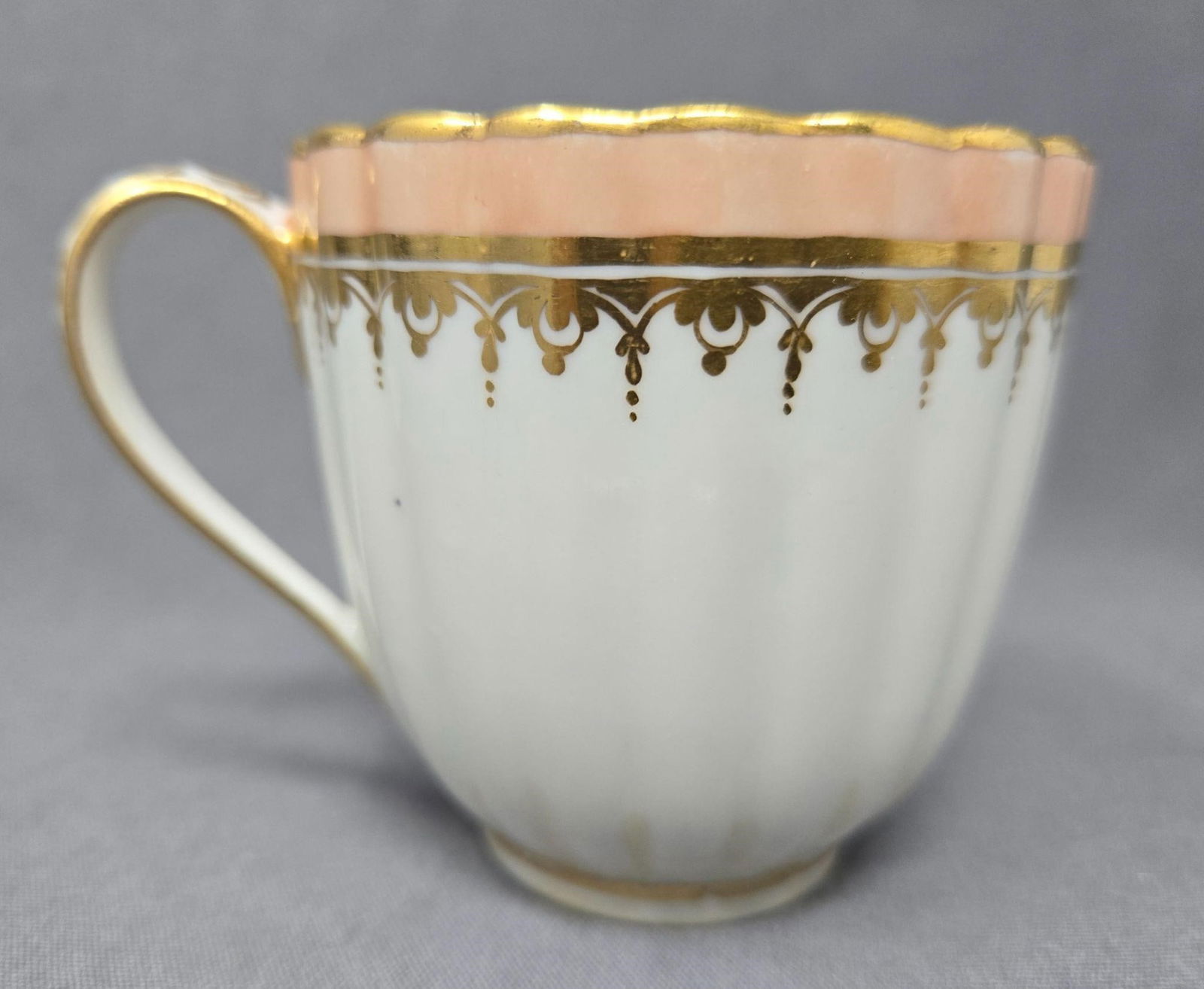 Old Derby Coffee Cup Pattern 84 C. 1784-1806: Antique Derby pattern 84 coffee cup. Circa 1784 to 1806. It has peach and gold floral pattern band at the top with a painted floral pattern handle and an inner band with a circle of gold leaves and a