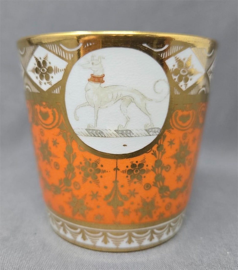 Chamberlain Worcester Coffee Can with Greyhound: Chamberlain Worcester coffee can with a family crest. There is a greyhound argent on a torse with the white dog signifying purity. The cup pattern is a peachy orange with gold flowers and garlands.