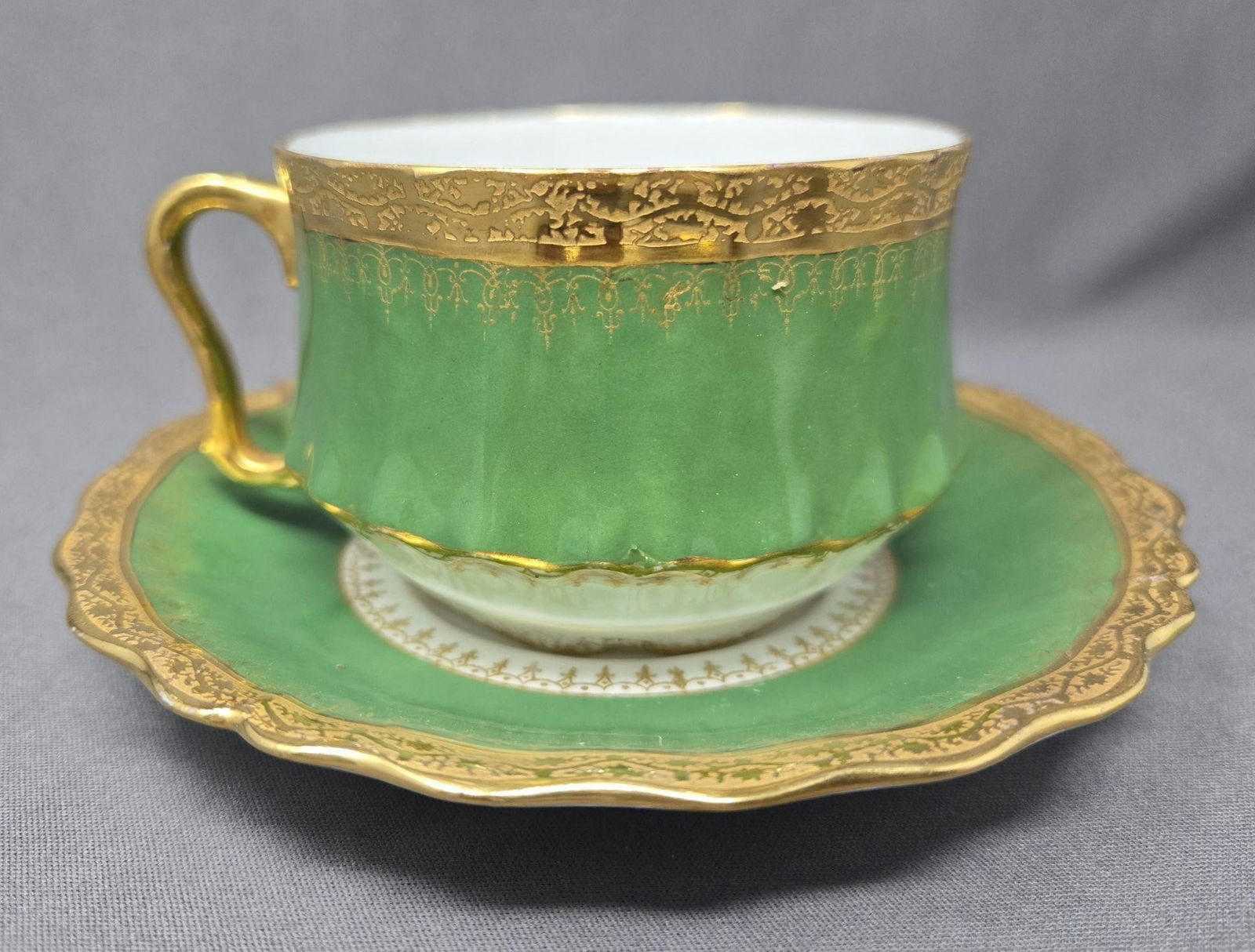 L S & S Limoges Cup and Saucer Green & Gold: Lewis Straus and Sons Limoges cup and saucer set. Green and white with ornate gold trim and encrusted decoration. Circa 1890 to 1920. Approximate Measurements: The saucer is 5 5/8 inches in diameter