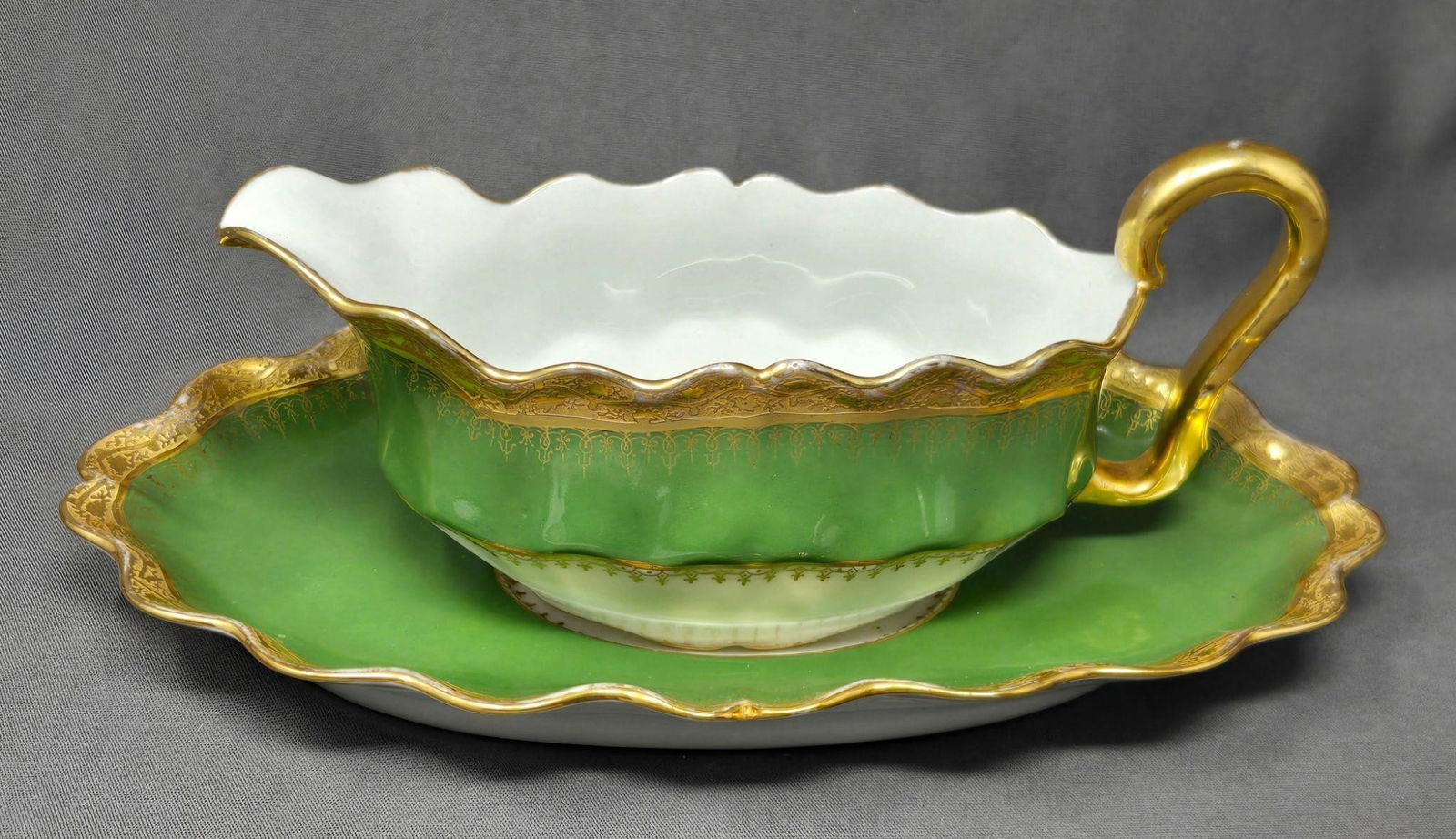Share L S & S Limoges Gravy Boat and Undertray: Lewis Straus and Sons Limoges Green and Gold gilt gravy boat and underplate. Circa 1890 to 1920s. Underplate has a chip on the underside as shown, there is also loss to gold on higher points. No other
