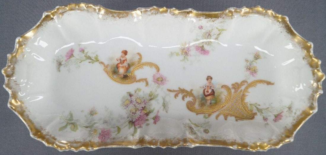 Limoges Watteau Scene Pink Floral Celery Dish: Antique French porcelain celery dish made in Limoges, France for Bour Bros in Canton, Ohio. Nicely decorated with small Colonial women and pink and white flowers with hand colored highlights. Has fanc