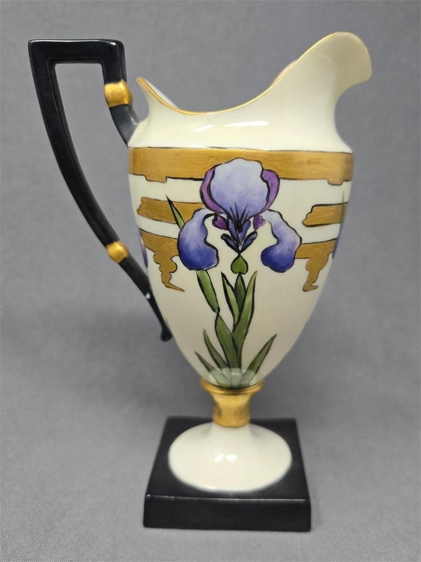 Lenox Belleek Iris Creamer 5 7/8" 1889-06: Lenox Belleek Tall Creamer on a square base. Hand painted iris's with green leaves a gold patterned background. Measures approximately 5 7/8 inches tall and 4 1/8 inches from handle to spout. The base