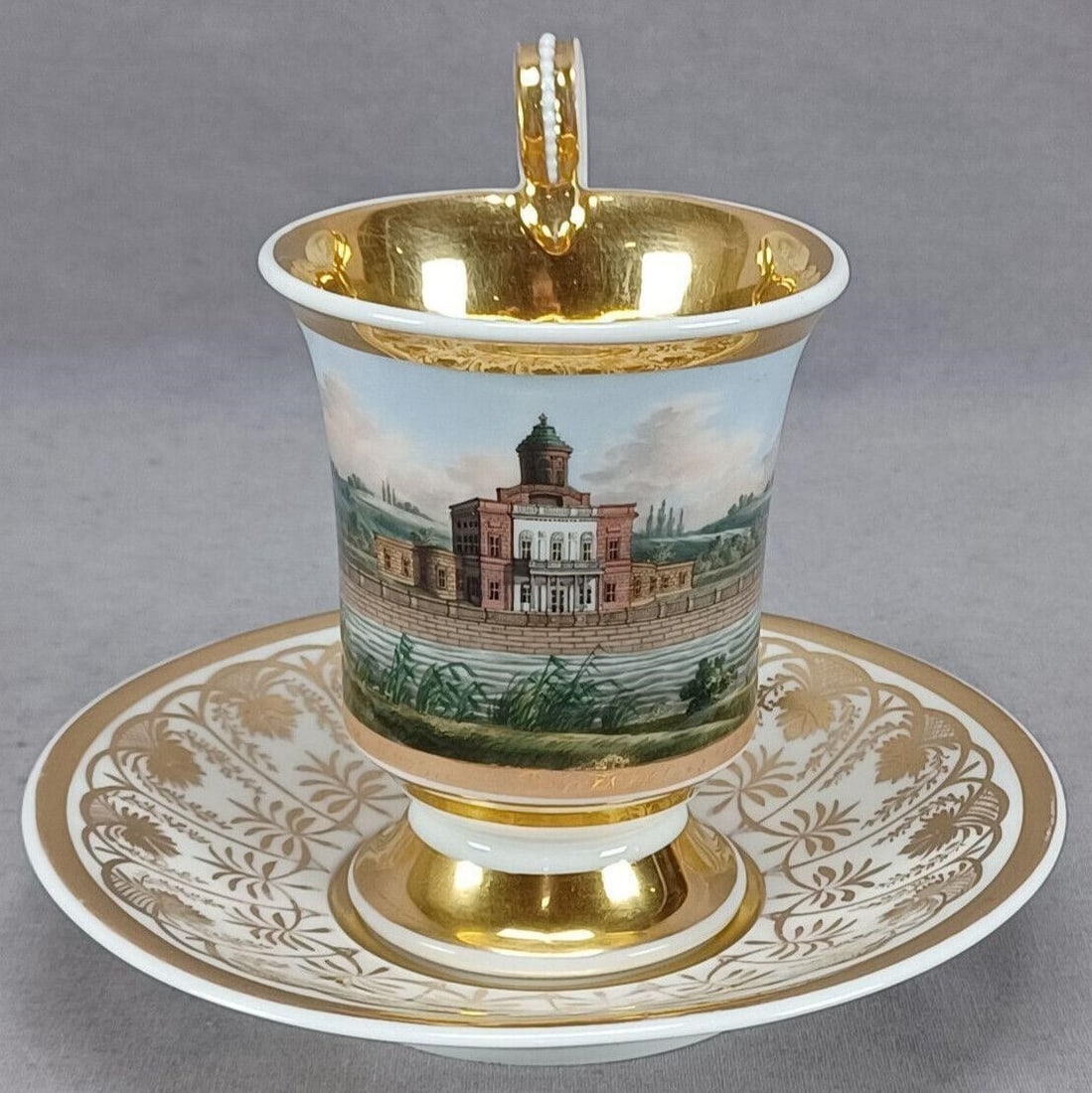 KPM Berlin HP The Marble Palace Cup & Saucer: Nice antique German porcelain cup and saucer. Decorated with a hand painted topographical scene depicting The Marble Palace in Potsdam framed in gold gilding. With gold arch and floral design around t