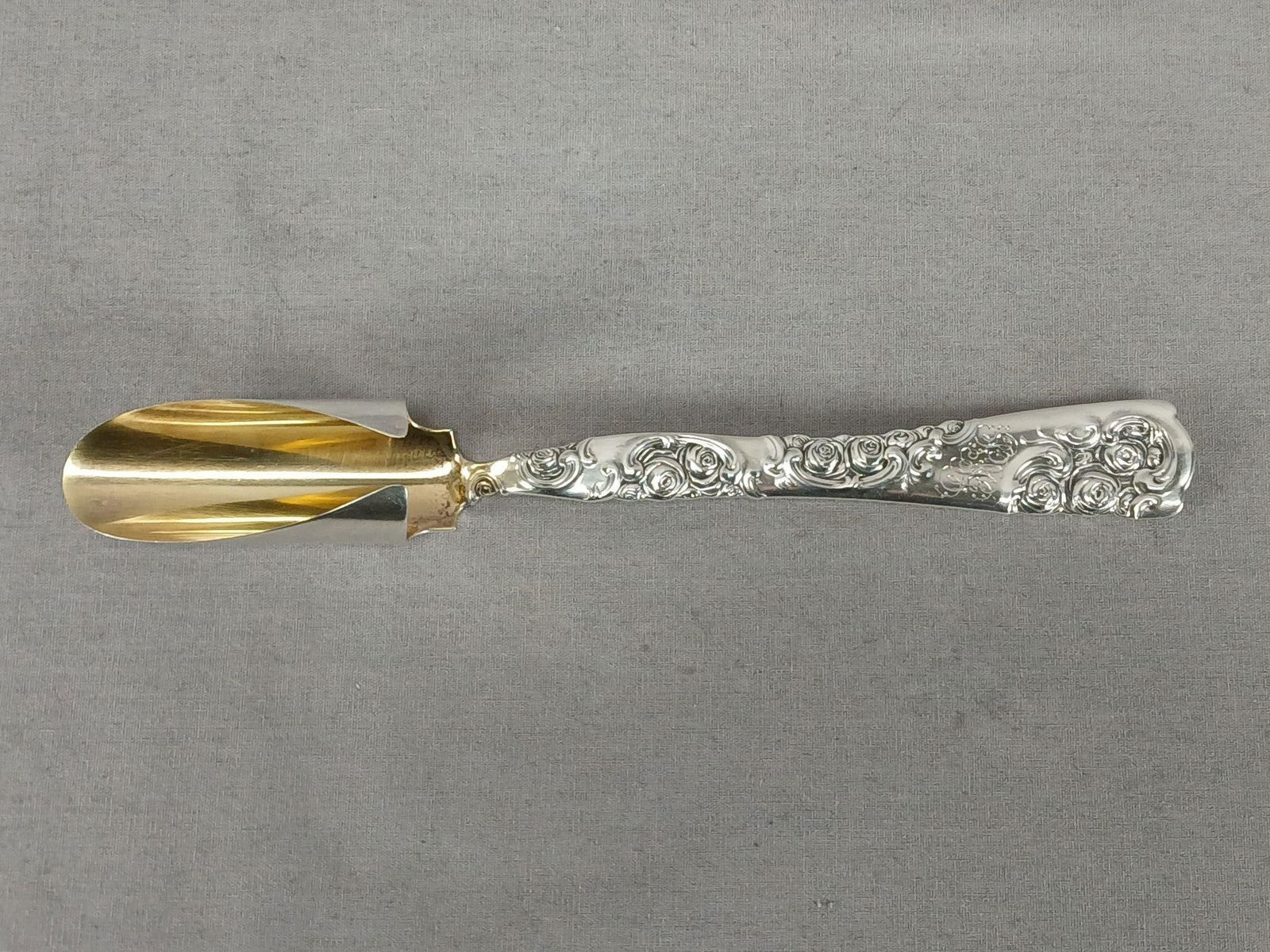 Whiting Roses & Scrolls Sterling Cheese Scoop: Antique sterling silver cheese scoop in the Roses & Scrolls pattern. Gold washed scoop. Engraved scripted monogram on the front of the handle. Has the hallmark for Whiting MFG Co, New York, 1866 to 19
