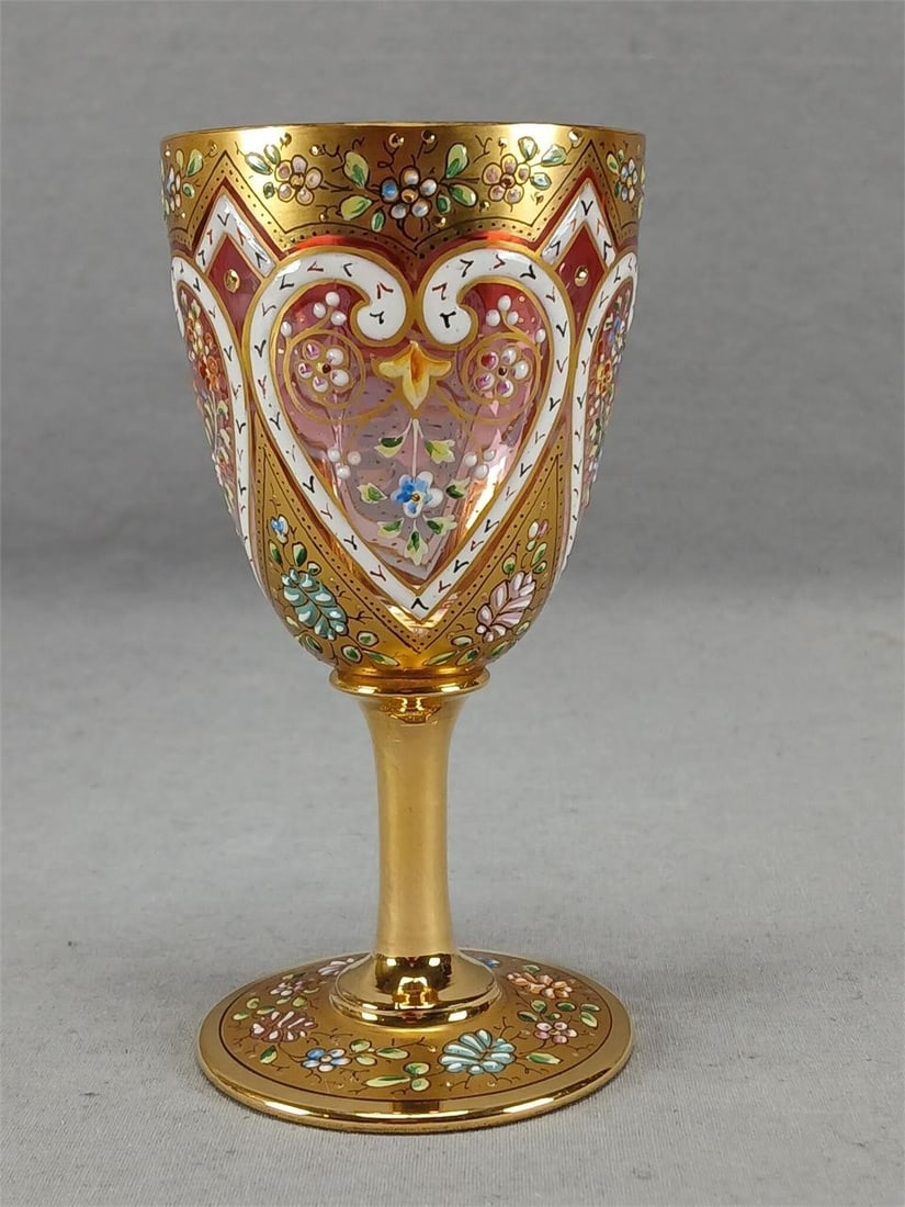 Harrach Floral Hearts Cranberry Wine Glass A: Antique Bohemian Harrach cranberry fading to clear wine glass. With enameled pink and blue flowers over gold above white enamel hearts with enameled flowers inside above heavy gold petals with enamele