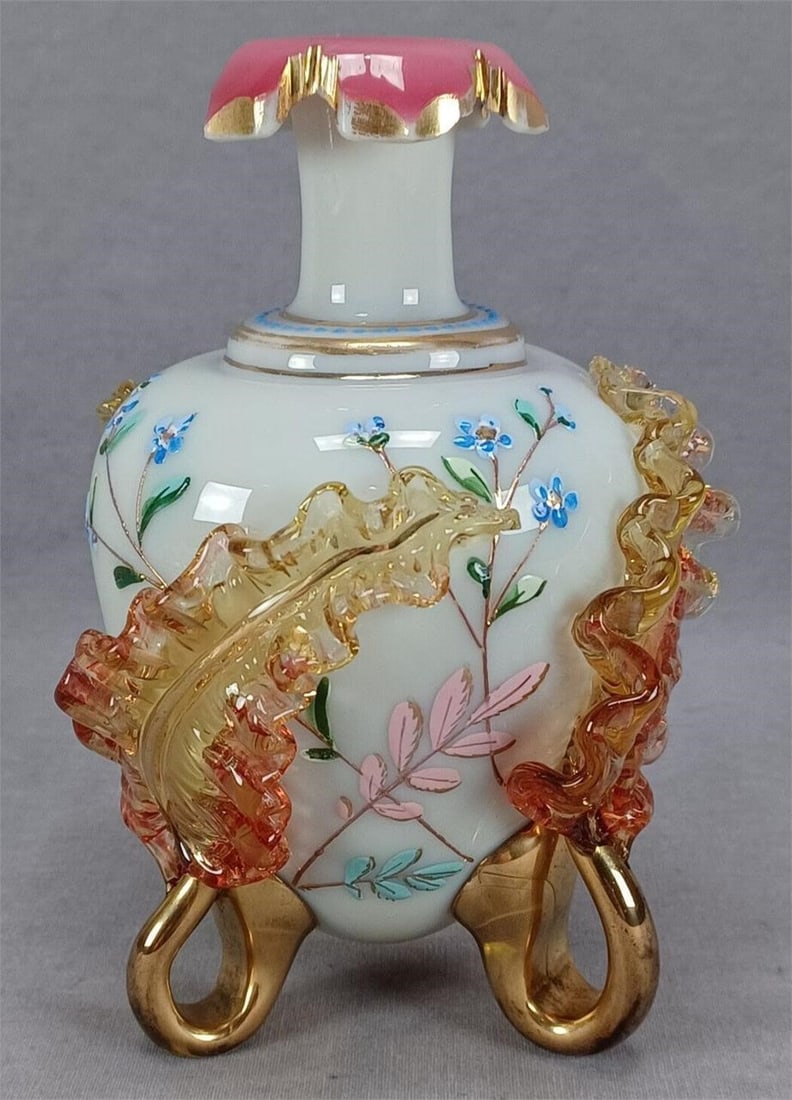 Harrach Enameled Applied Leaves & Gilt Vase: Antique Bohemian blown off white custard cased pink glass vase. With enameled blue flowers with green, turquoise, and pink leaves. Has blue enamel beading and gold bands below the neck. The pink casin