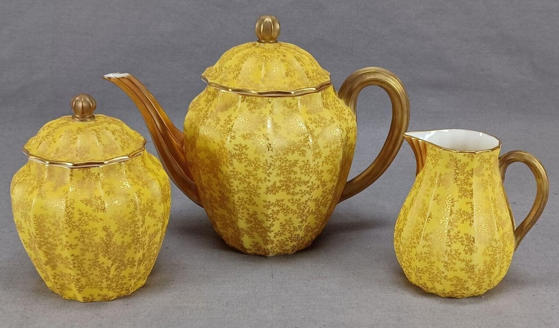 Royal Worcester Yellow Teapot Creamer & Sugar: Nice antique British bone china tea trio set including teapot, creamer and sugar. Decorated with gold fern leaves over a yellow background. Gold gilding to the finials, handles, and spouts. Marked on