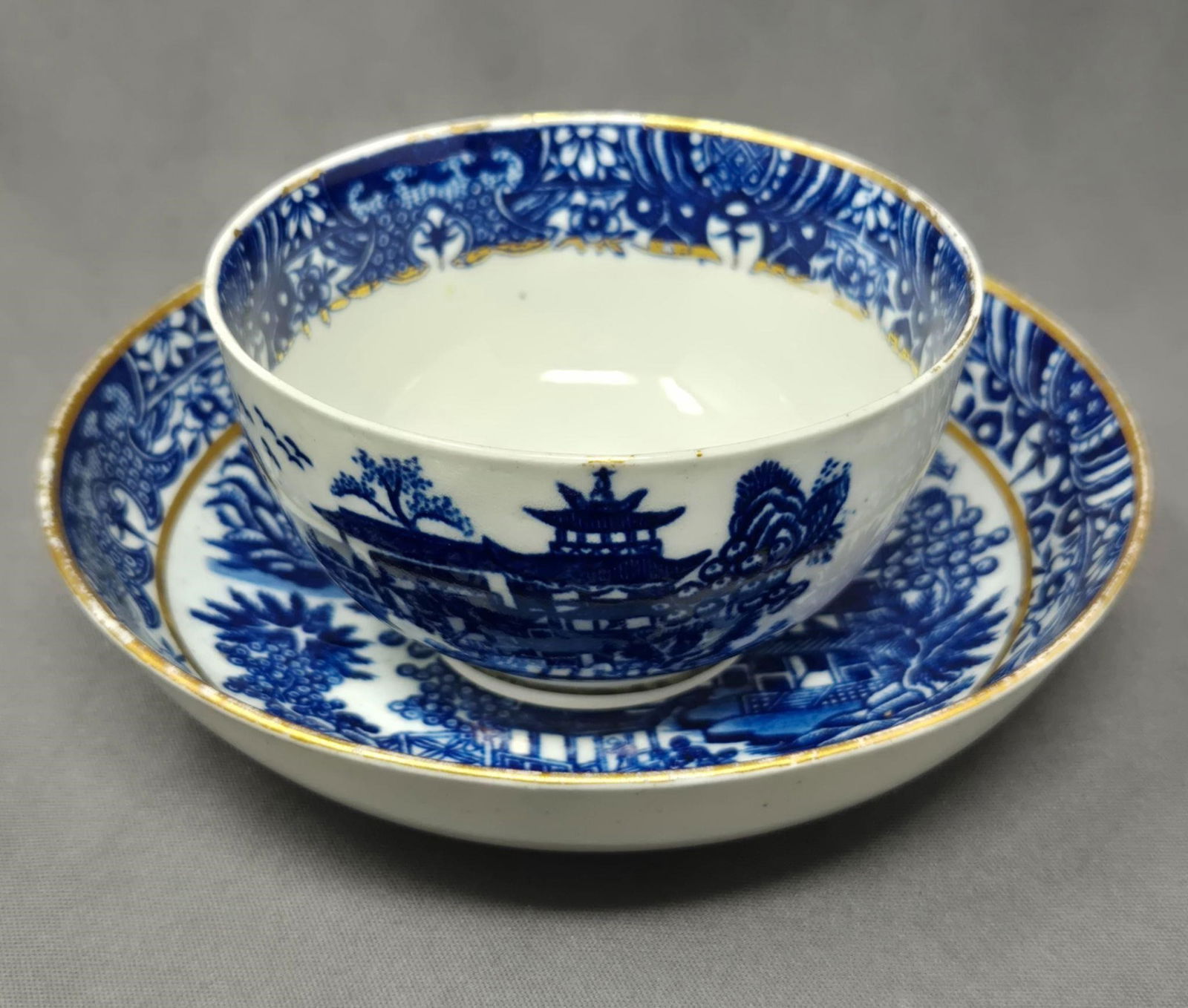 Dr Wall Handless Cup and Saucer 18th C.: Dr Wall handless cup and bowl saucer with blue Asian scenery. Gold gilt on rims and inner band. No chips or cracks or crazing. There is some loss to the gold gilt in spots. Circa 1751 to 1776. Saucer