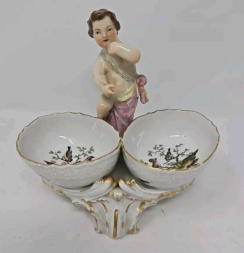 Antique Figural KPM Salt Dish Hand Painted Cherub: KPM double salt with a Cherub figure. Egg-shaped salts on rococo style base. Salts are decorated with hand painted butterflies and birds. Measures approximately 4 6/8 inches tall 5 1/4 inches long and