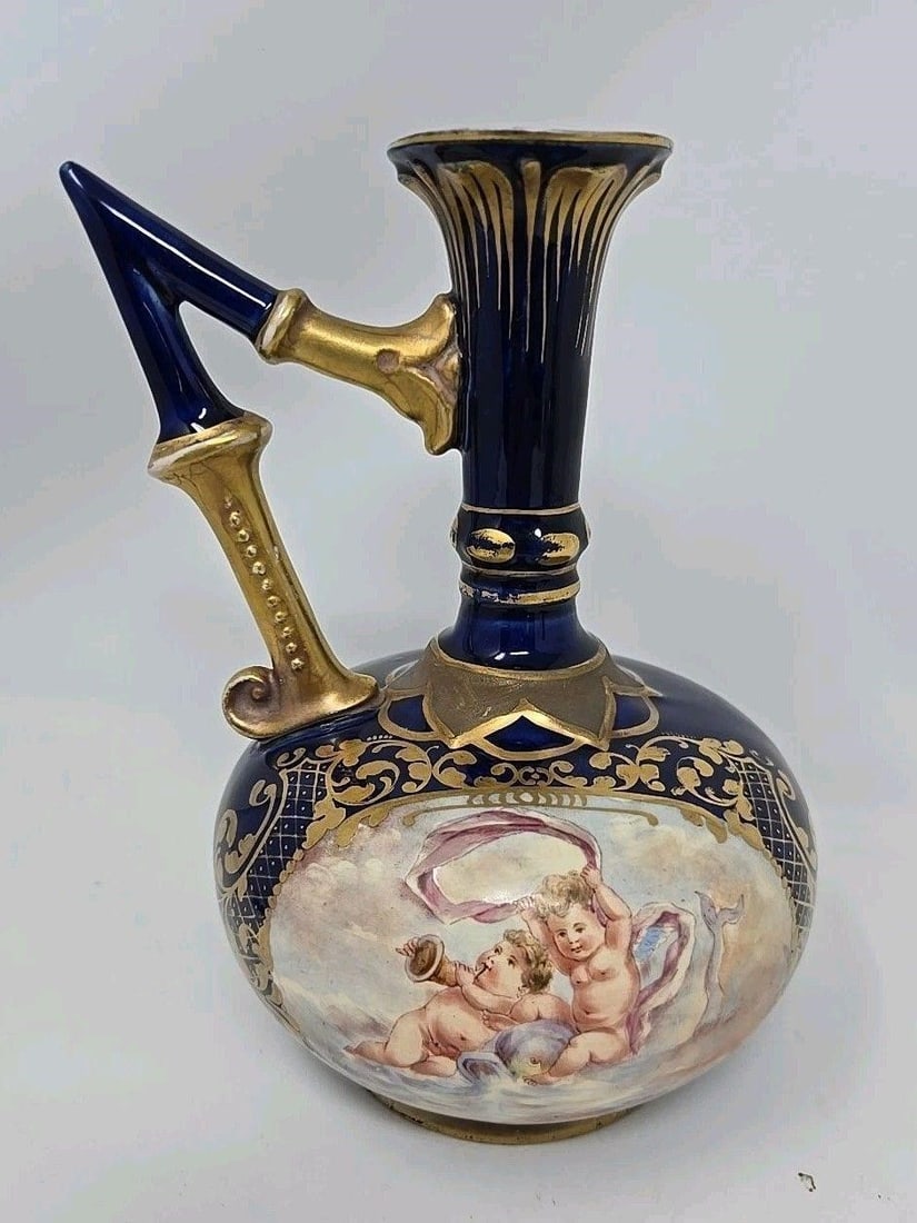 Fisher Earthenware Vase C. 1890 7 1/2" Cherubs #1: J. Fisher of Budapest Hungary earthenware vase. Painting of cherubs on clouds on a cobalt blue case with gold accents. Measures approximately 7 1/2 inches tall and 5 1/4 inches wide. There is crazing