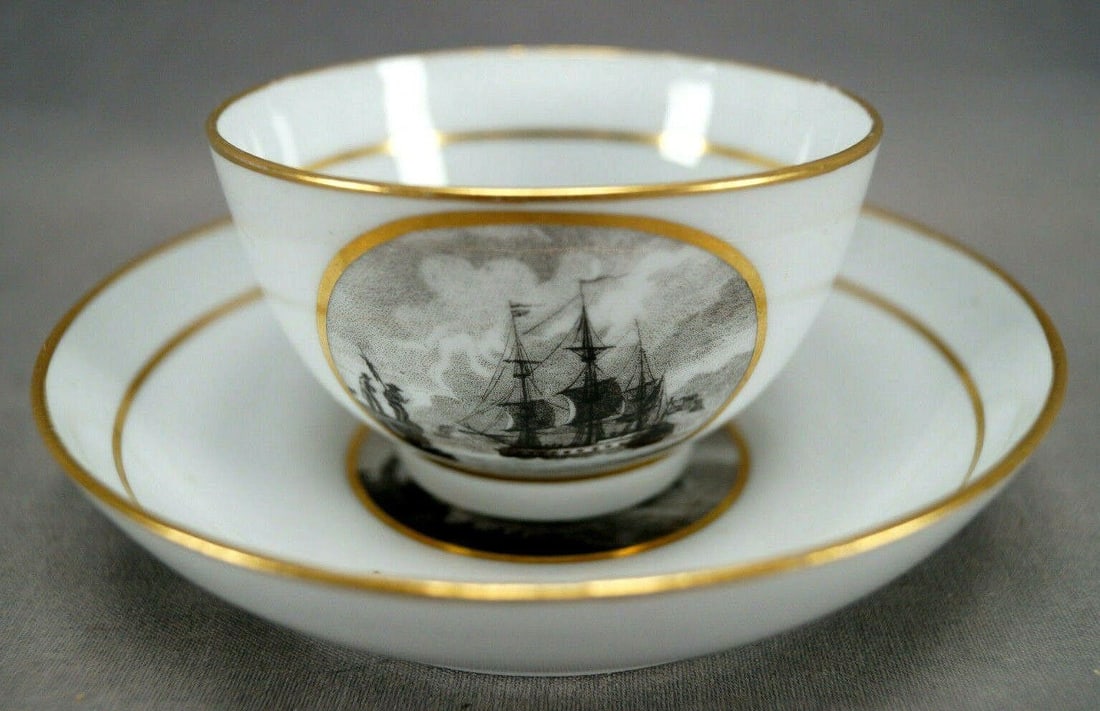 Thomas Wolfe Maritime Ship Tea Bowl & Saucer: Nice antique porcelain tea bowl and saucer. Decorated with a bat print of a maritime scene with a ship and two figures standing on a cliff. Gold gilt bands. Unmarked. Made by Thomas Wolfe / Factory Z.