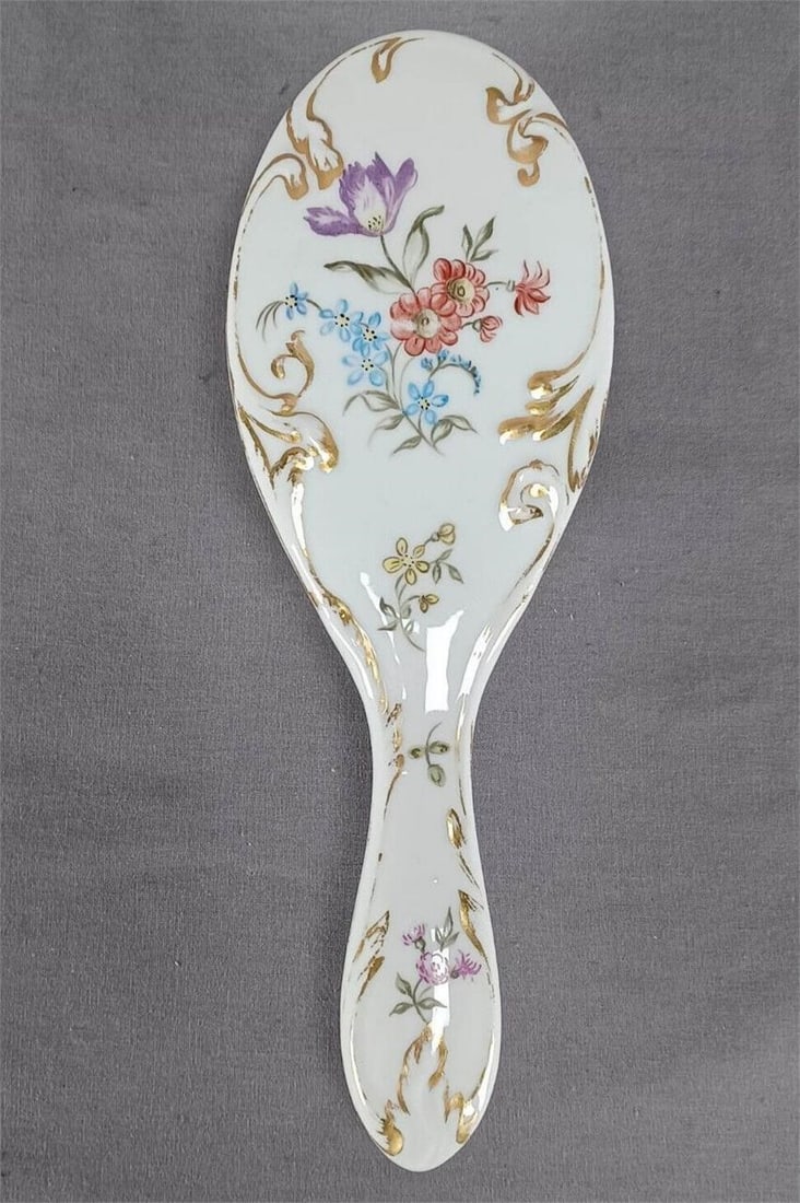 Limoges Hand Painted Floral Porcelain Hair Brush: Antique porcelain handled and backed hair brush. Decorated with hand painted flowers in the Dresden style in purple, red, blue, and yellow. With relief molded scrollwork with gold highlights. Marked D