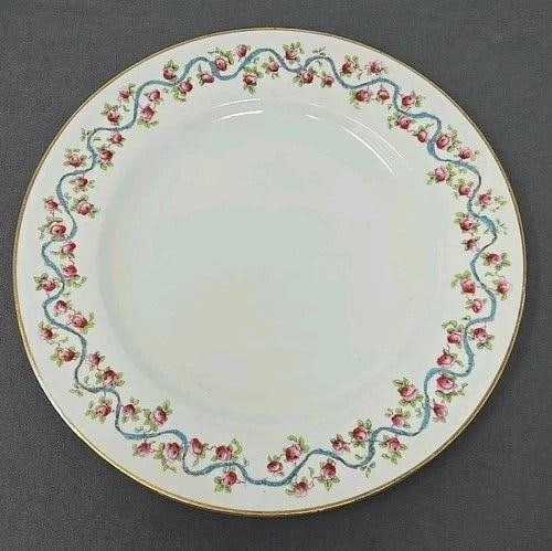 George Jones and Sons Plate England Roses & Ribbon: George Jones and Sons dinner plate with a rose border with a blue ribbon. Measures approximately 9 7/8 inches diameter. No chips or cracks. There is a loss of gold gilt and scratches from use. Circa 1
