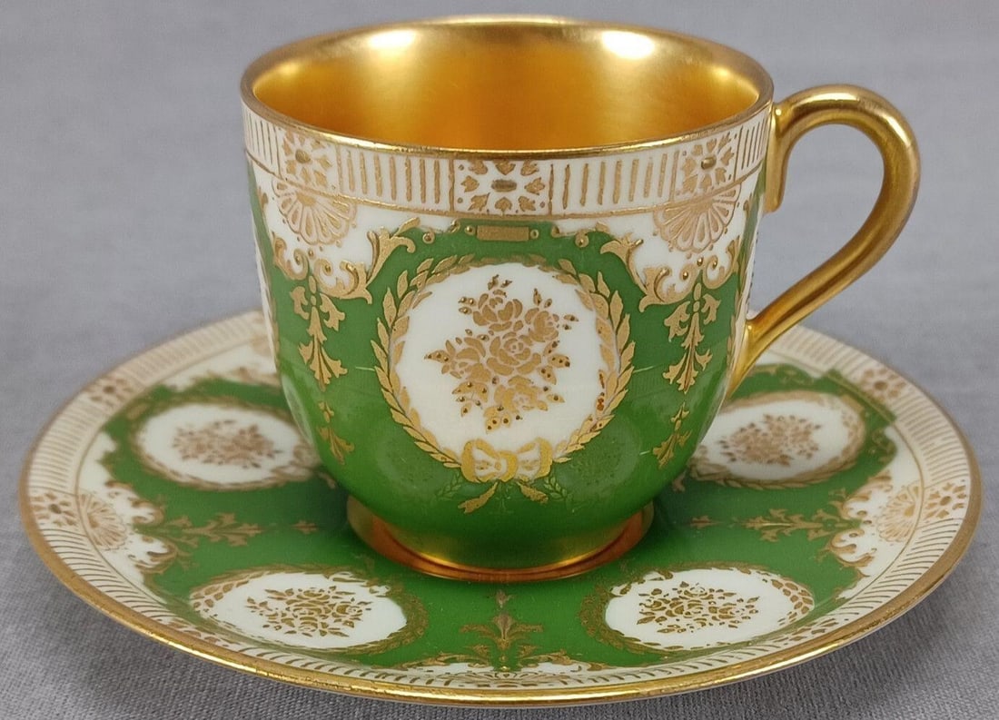 Royal Doulton Green Gold Demitasse Cup & Saucer A: Antique British bone china demitasse cup and saucer. Decorated with gold roses with small gold beads in white medallions with gold wreaths with bow and partially raised gold scrollwork over a green ba