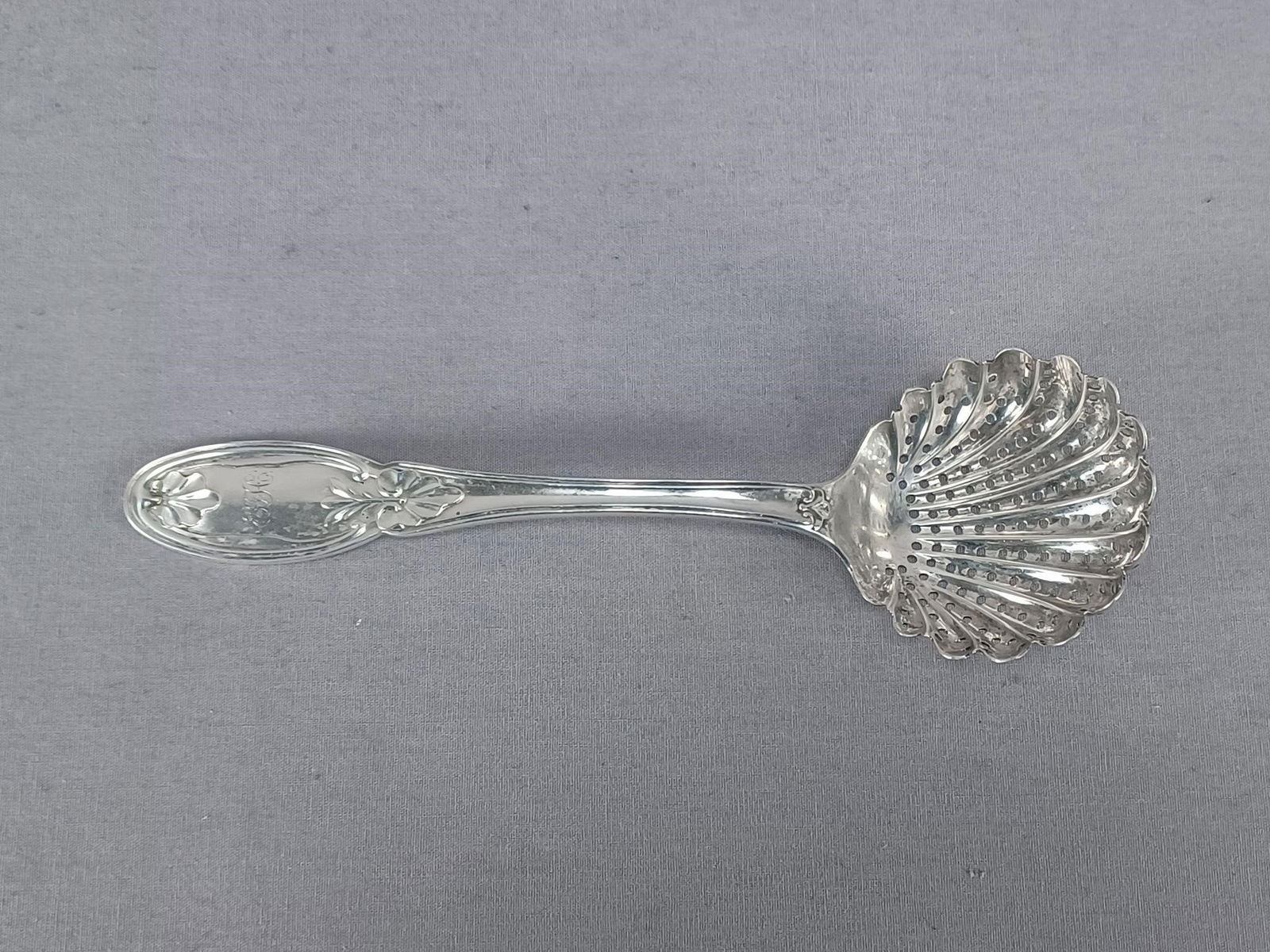 T&L Philadelphia Coin Silver Sugar Sifter Spoon: Antique American coin silver sugar sifter spoon. Repousse leaf pattern on the handle with engraved scripted EGH monogram in the center. Hallmark of an eagle, thistle, and harp for for Taylor & Lawrie,