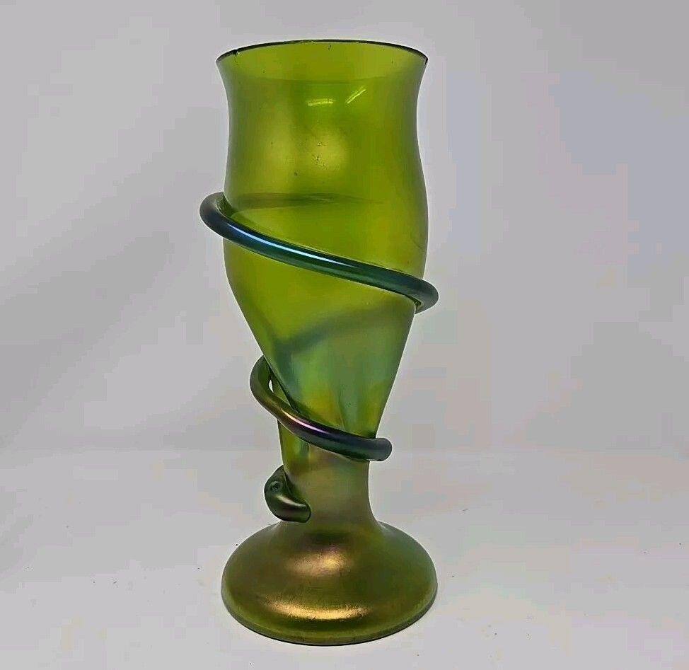Loetz Green Iridescent Snake Vase c.1900: Green iridescent Loetz snake vase. It is a pinched vase with a snake wrapped around it. Iridescent green, with blue and purple. There are several chips on the rim all around the top and a pot stone on