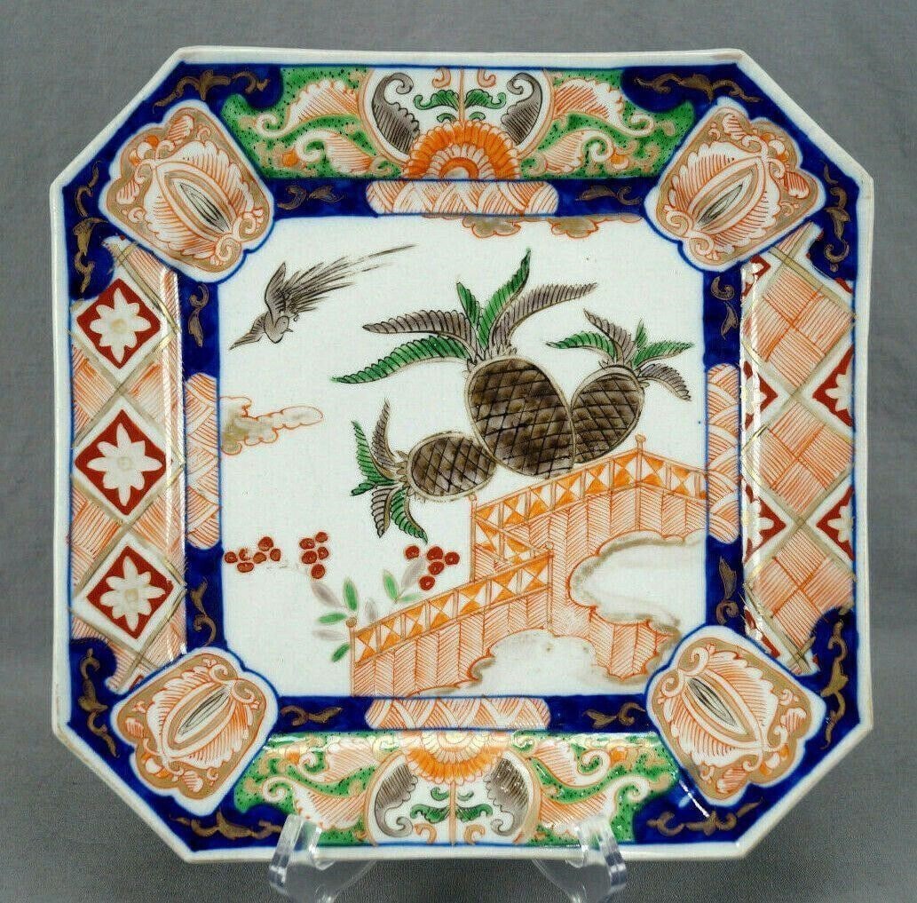 Japanese Imari Birds Pineapples 10 3/8" Plate: 19th century Japanese Imari square porcelain plate. Decorated with hand painted birds, pineapples, and a fence in grey, black, green, red, and orange in the center. With a cobalt blue border with red,